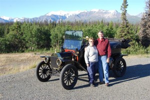 a couple near old automobile out near the mountains