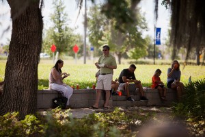 People eating crawfish at park sitting on stone wall