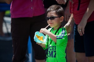 little boy in green shirt holding a straw and a bowl of orange slices