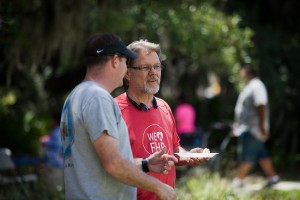 two men talking one wearing a we heart FHR shirt with bluetooth