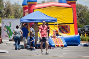 Dad with we heart FHR shirt walking by a group near bouncy castle