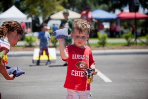 little boy wearing Kansas City Chiefs shirt playing bean bag toss