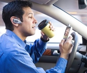 male driver distracted by coffee cell phone and bluetooth while driving